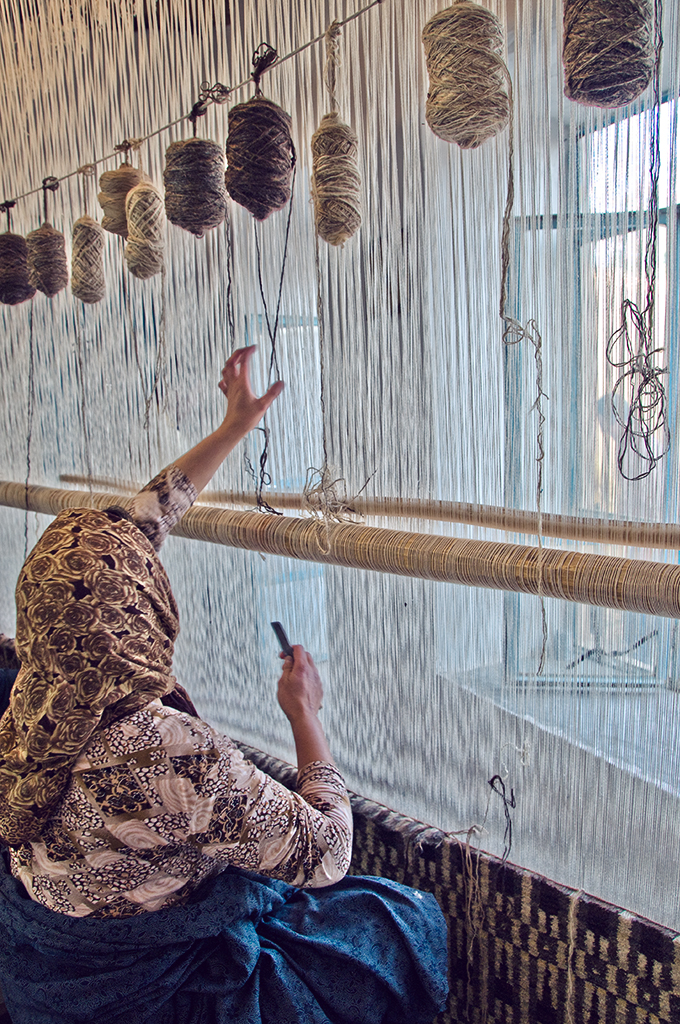 An artisan reaches to skeins of all natural totally organic pure wool for handknotting this functional work of art