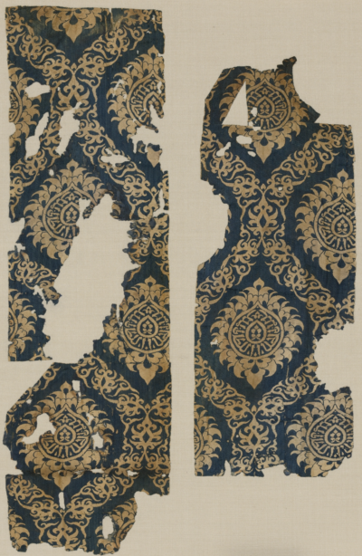 Influenced by Chinese and Mongol prototypes, this fragment shows a repeating pattern of an ogival vine scroll that undulates around Chinese-style lotus blossoms enclosing a naskh inscription.