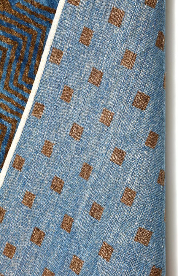 Luxurious handwoven wool carpet from Persian Fat Tailed Sheep in rich brown on blue background from organic vegetable dyes