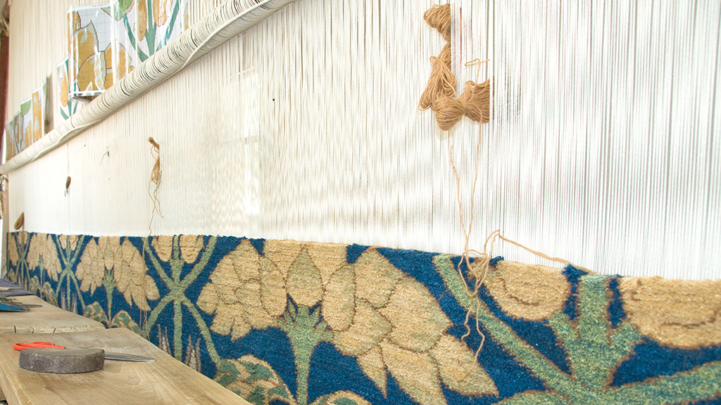 Weaving with the Persian knot, a handknotted carpet in wool with blue and cream, a work in progress on the loom.