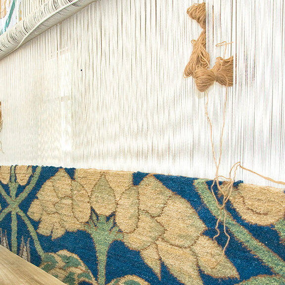 Weaving with the Persian knot, a handknotted carpet in wool with blue and cream, a work in progress on the loom.